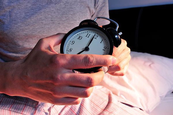 Man turning off alarm clock