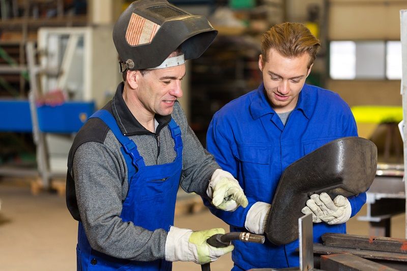 Instructor teaching trainee how to weld metal-cm