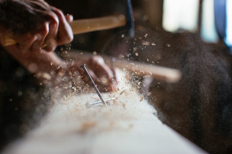 Close-up-of-man-hammering-a-nail-into-wooden-board-cm