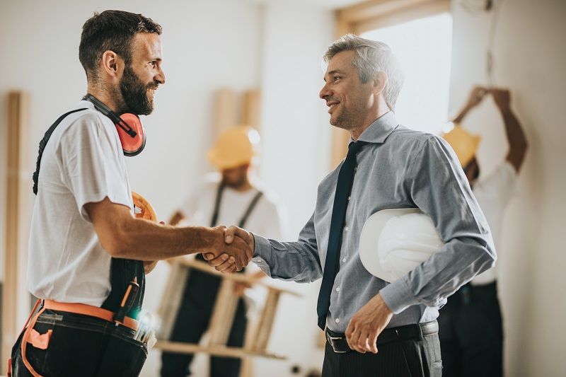 Happy-manual-workers-shaking-hands-with-an-architect-at-construction-site-cm