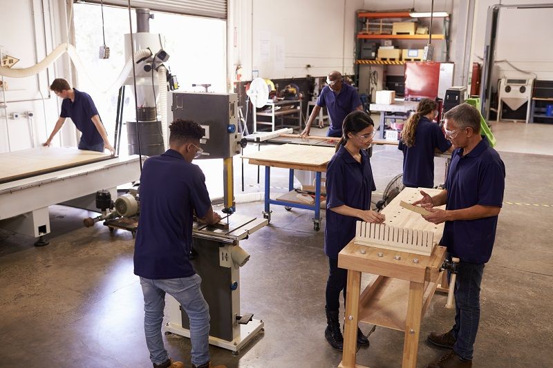 Carpenters-Working-On-Machines-In-Busy-Woodworking-Workshop-cm