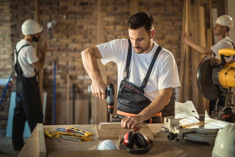 Manual-worker-using-drill-while-making-home-improvements-on-construction-site-cm