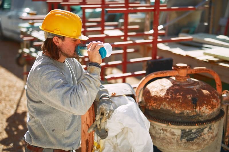 Construction worker on a heavy site doing hard work and drinking water. -cm