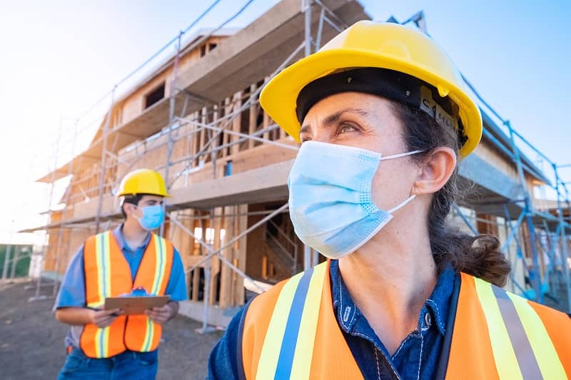 Mature female construction worker looking at the camera wearing a protective face mask -cm