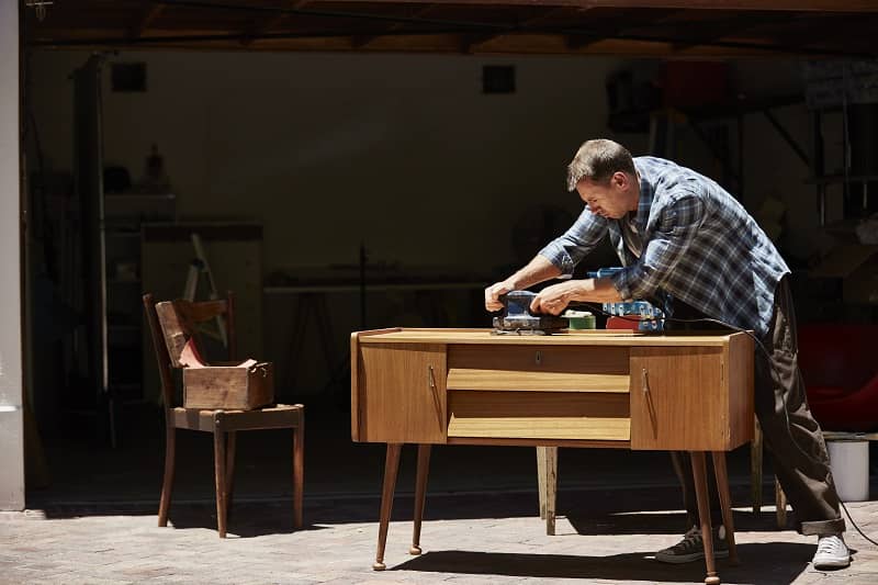 Man polishing furniture outside house-cm