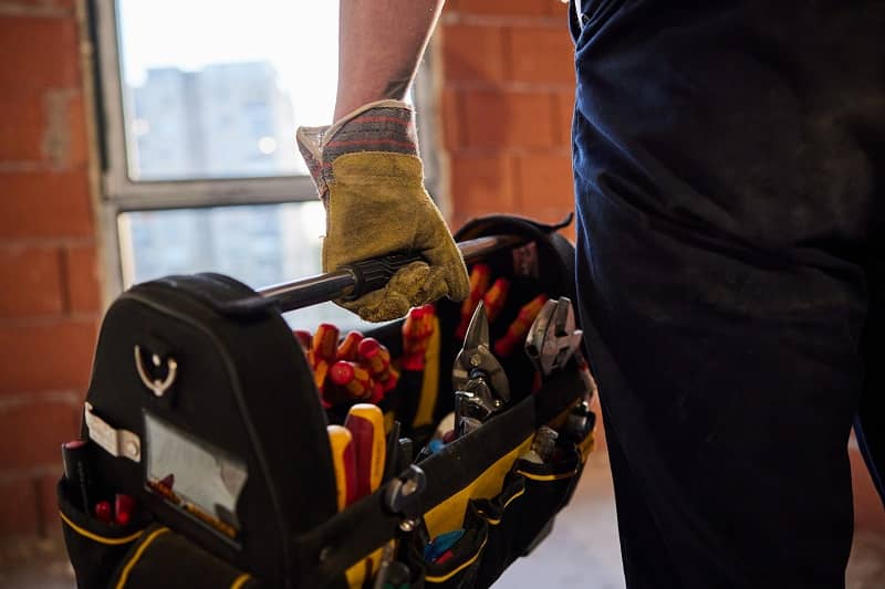 Close up of unrecognizable manual worker carrying toolbox-cm