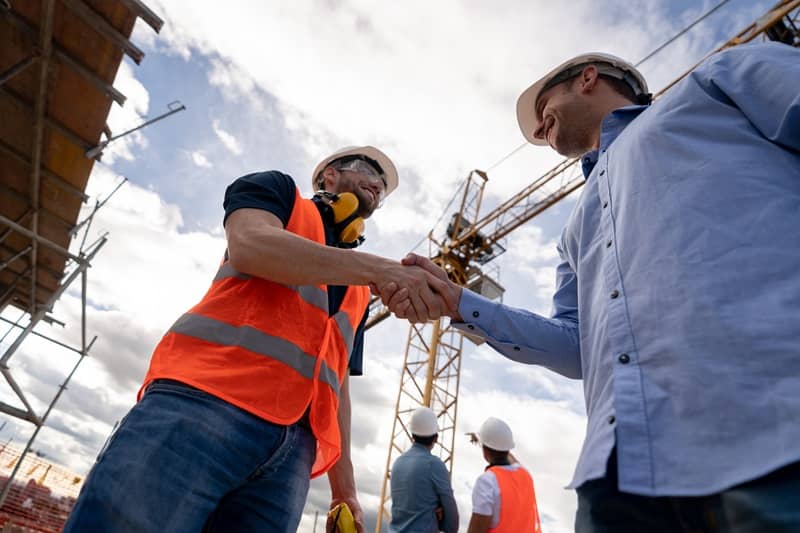 Architect handshaking with a construction worker at a building site-cm