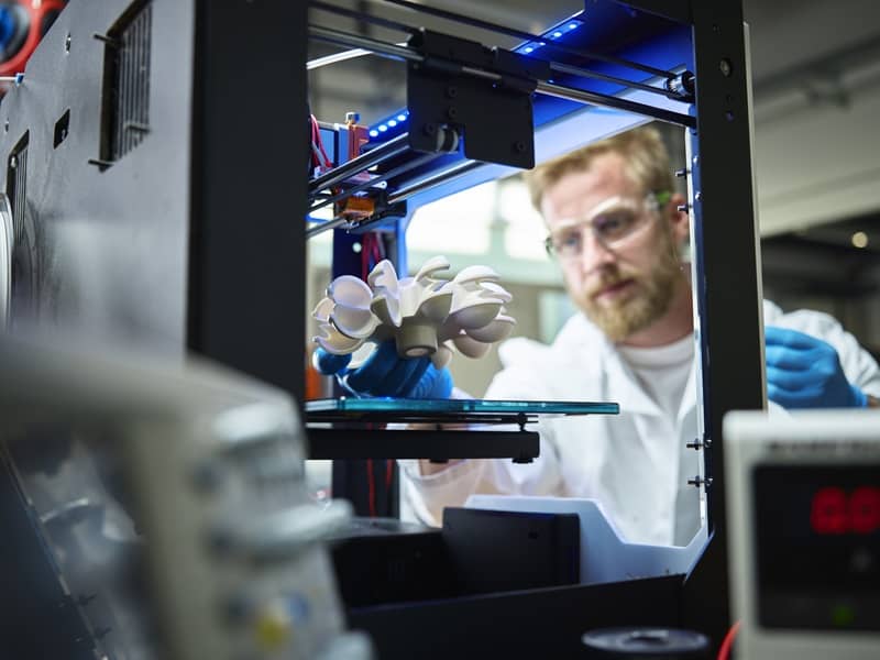 Technician with turbine wheel being printed in 3d printer-cm