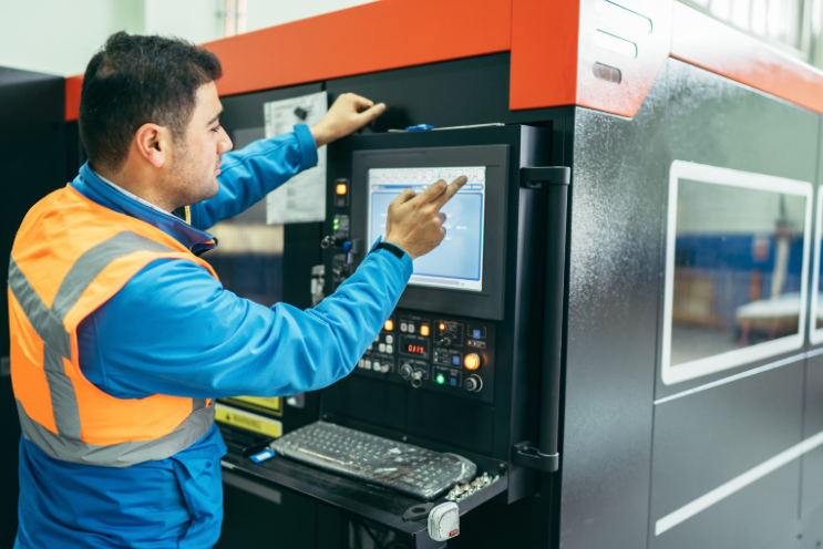 Worker operating CNC machine as part of evolving manufacturing industry trends