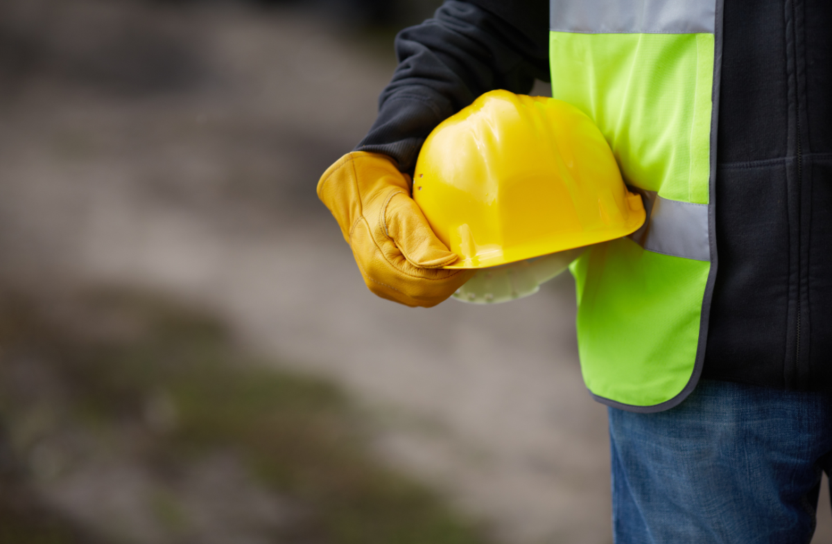 Construction and industrial staffing worker in safety vest holding a yellow hard hat
